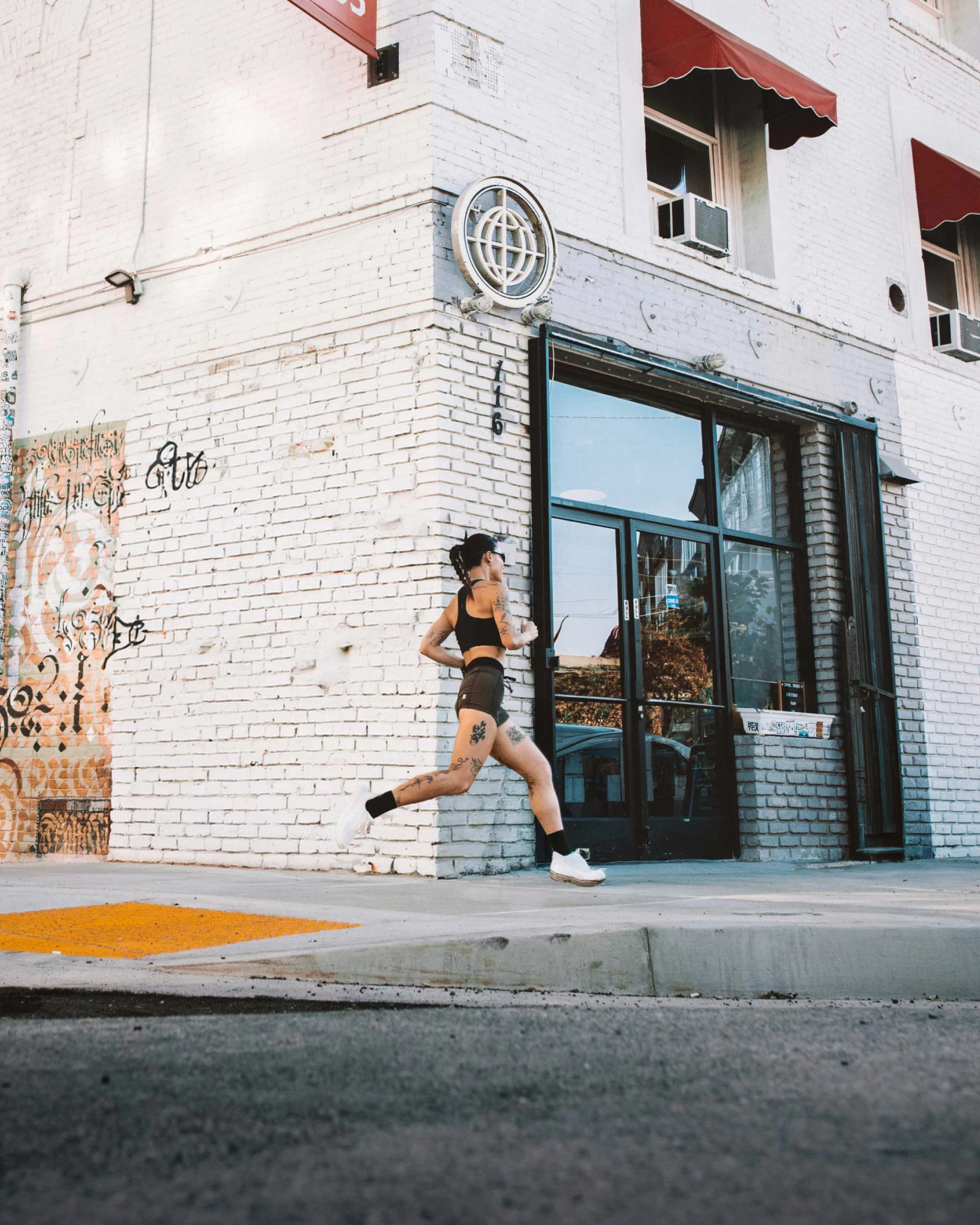 A woman runs past a white brick building on a city street