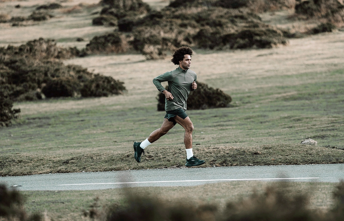A runner crosses open moorland beside a road