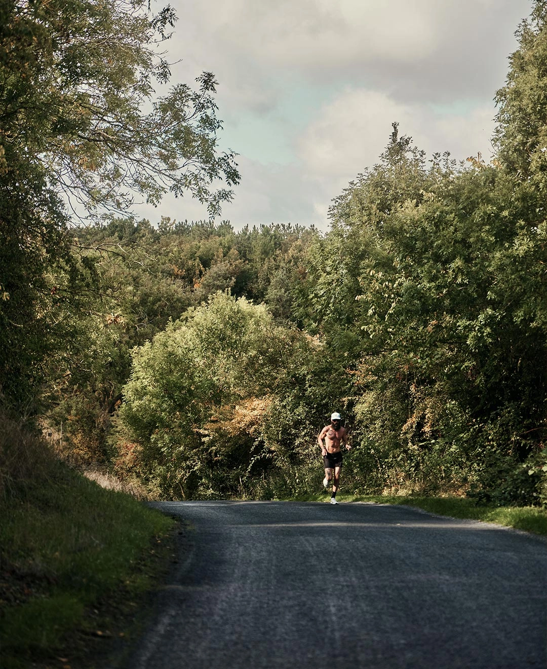 A lone runner on a tree-lined road