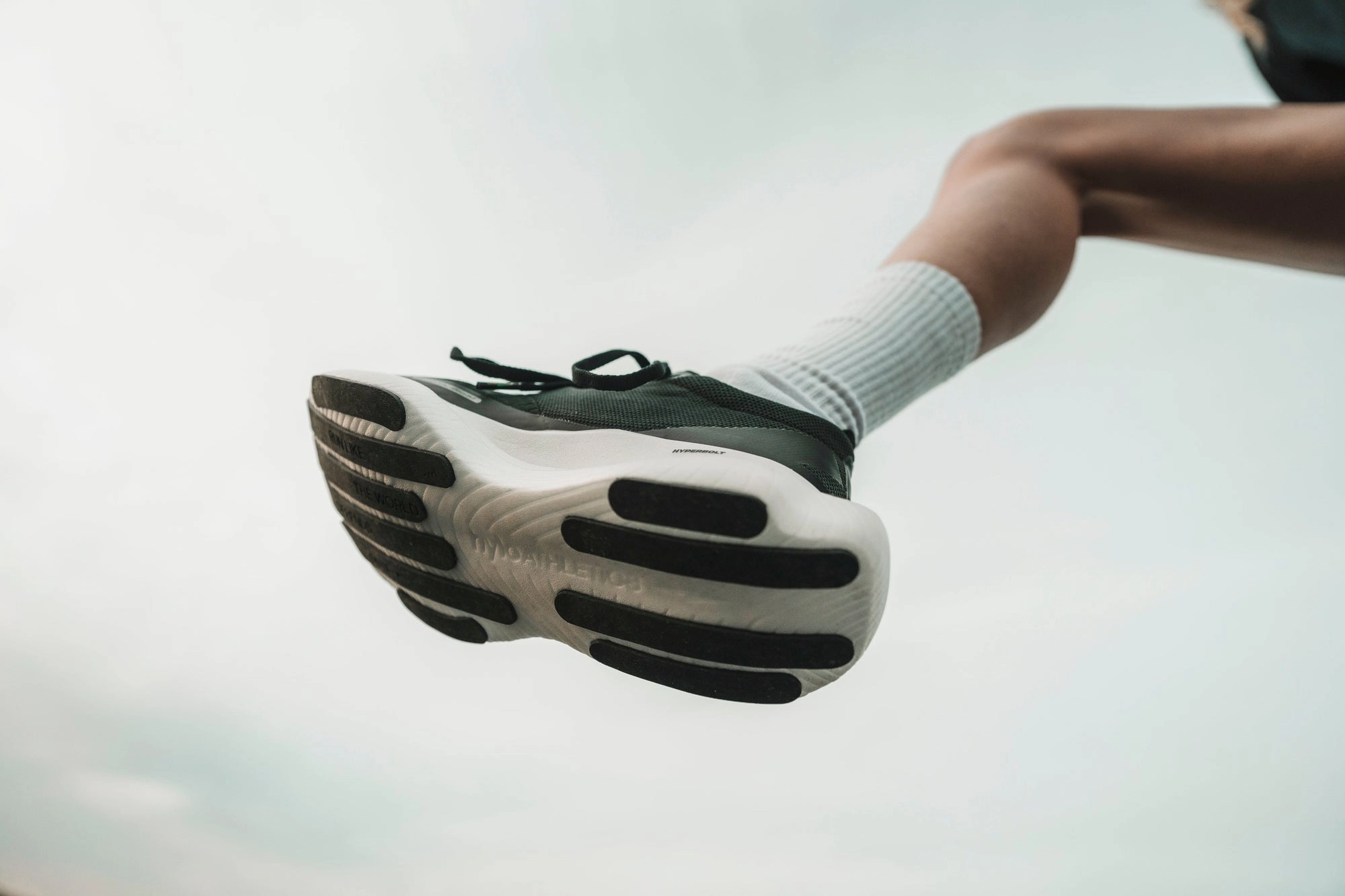 The sole of a hylo shoe mid-stride against a pale sky