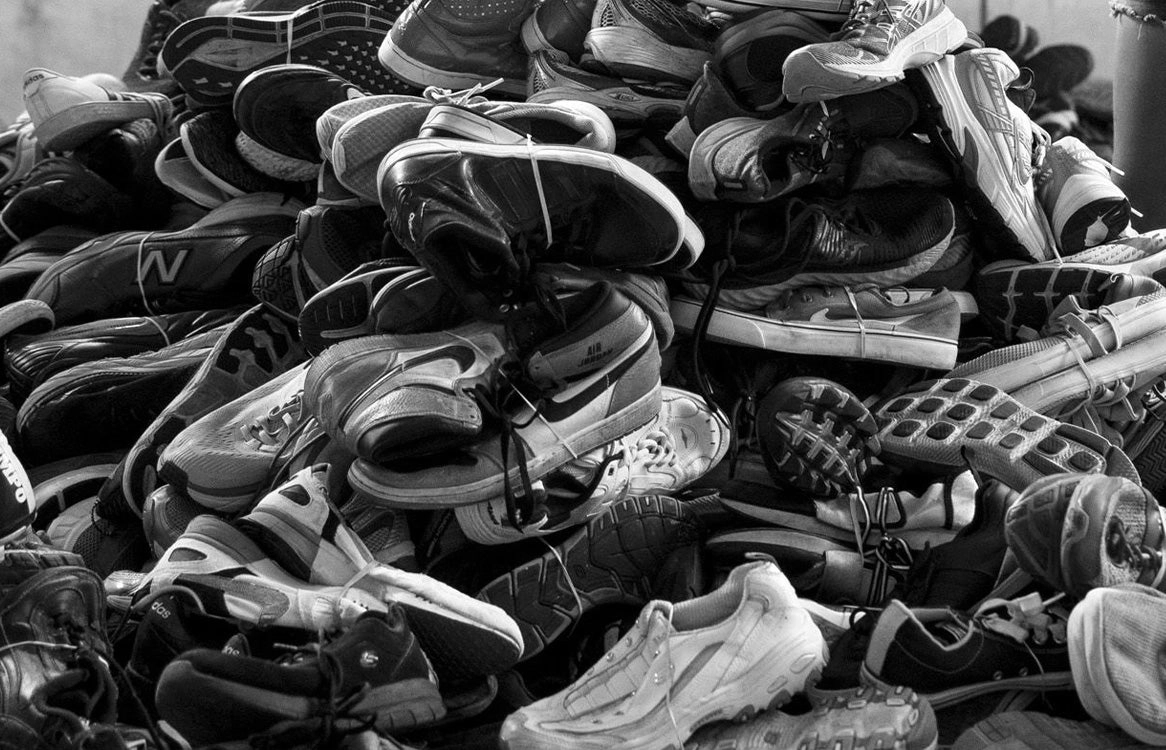 A heap of worn-out running shoes, in black and white